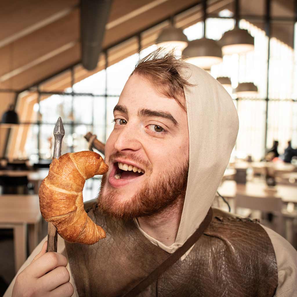 William Tell bites into a croissant stuck onto his arrow