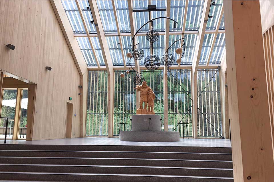 Blick in die Eingangshalle mit Tellskulptur und Holz-Glasdach