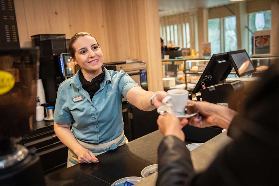 Barista reicht Kaffeetasse über den Bartresen