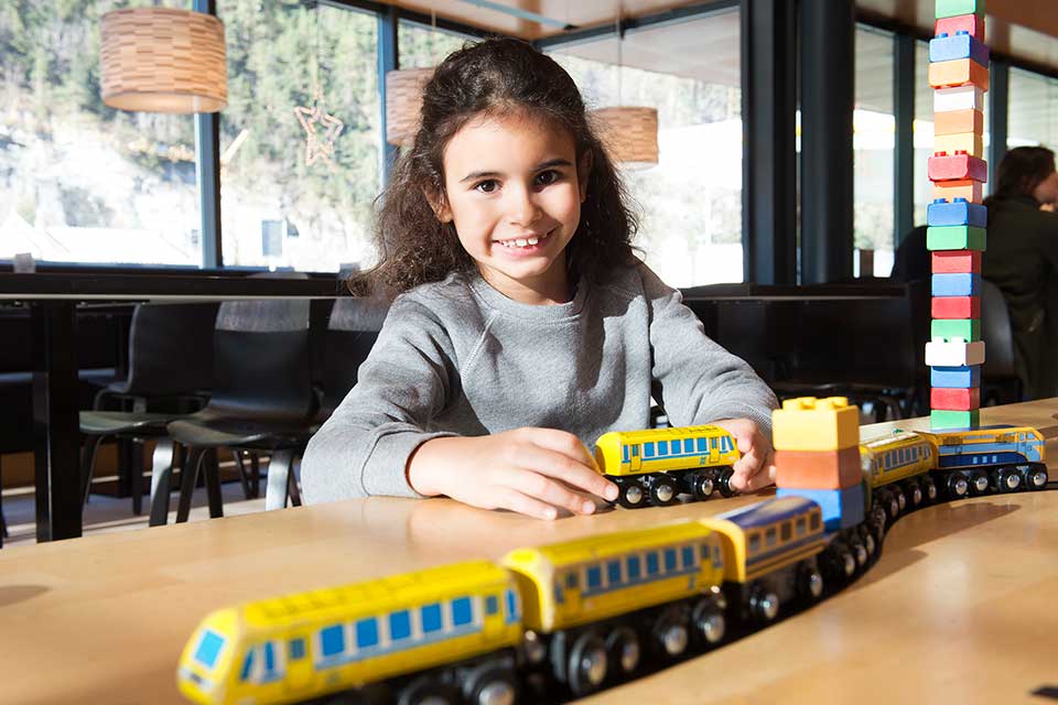 Girl plays with colourful wooden train set